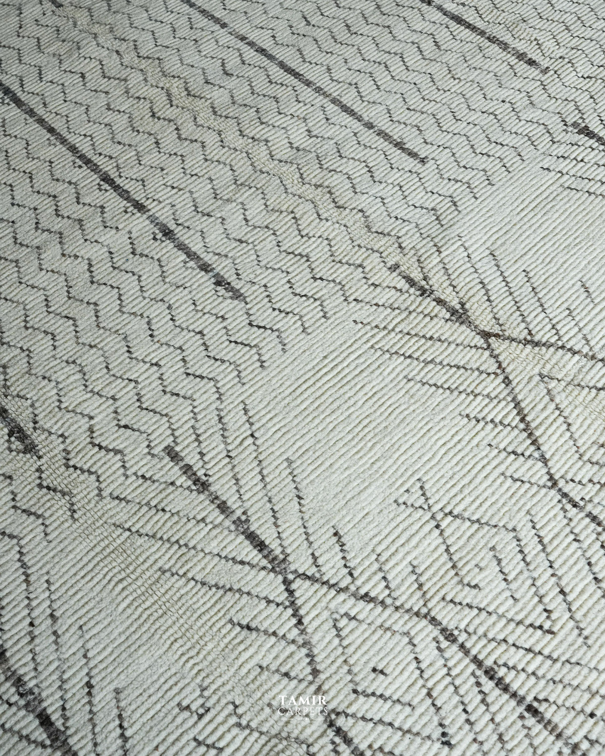Close-up of a woven textile surface with a light warm off-white base and dark charcoal geometric linear patterning.