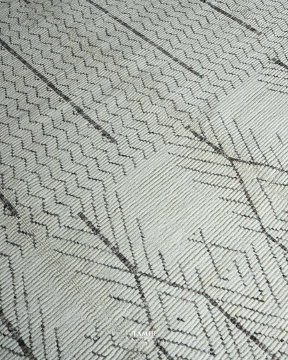 Close-up of a woven textile surface with a light warm off-white base and dark charcoal geometric linear patterning.