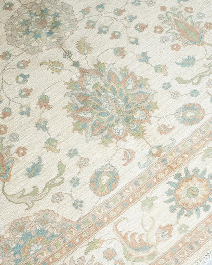 A close-up of a traditional patterned rug with an ivory base and floral motifs in muted blue, sage green, and peach.