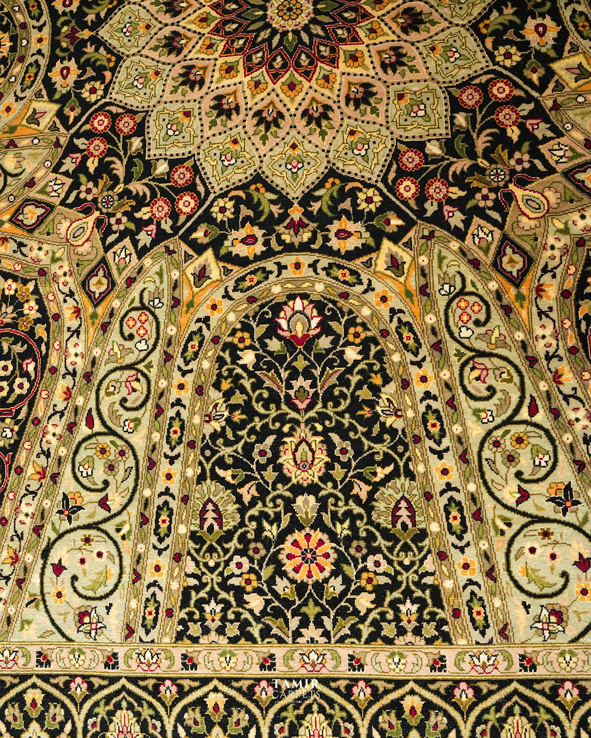 An ornate Persian-style rug with intricate floral and geometric patterns in black, beige, green, and red.