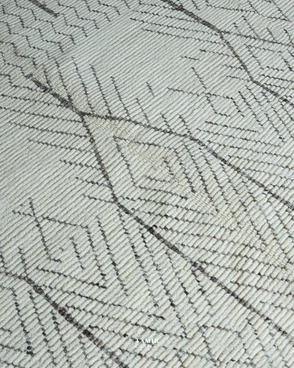 A close-up of a woven rug or textile with a geometric pattern in off-white and dark gray.
