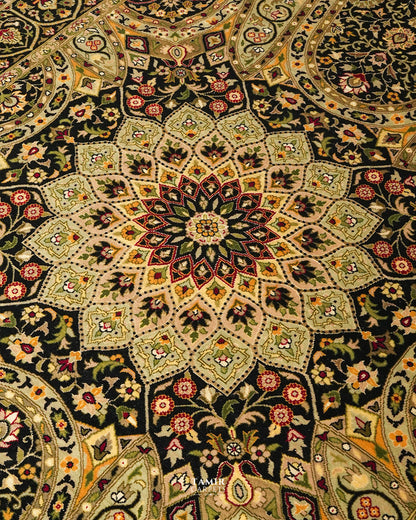 A close-up of an ornate Persian-style rug featuring a large central floral mandala pattern in black, beige, green, red, and gold tones.