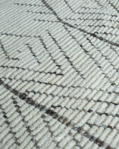 Close-up of a textured area rug with a cream-colored pile and a dark brown geometric woven pattern.