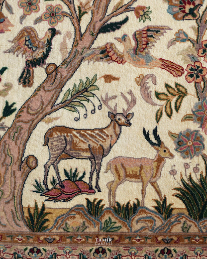 Close-up of a woven textile or rug pattern featuring deer, birds, floral motifs, and tree branches on an off-white background, with the brand name TAMIR CARPETS visible near the bottom.