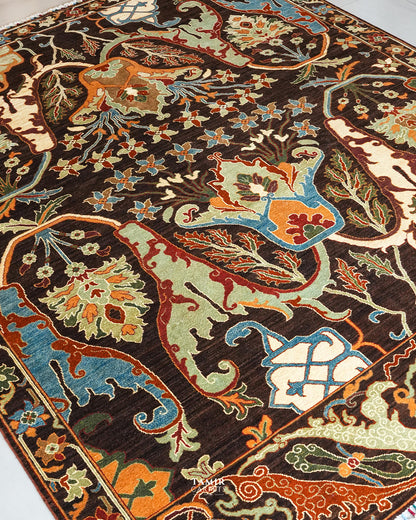 A close-up of an ornate area rug with a dark brown background and intricate floral and scroll motifs in beige, light green, orange, and blue.