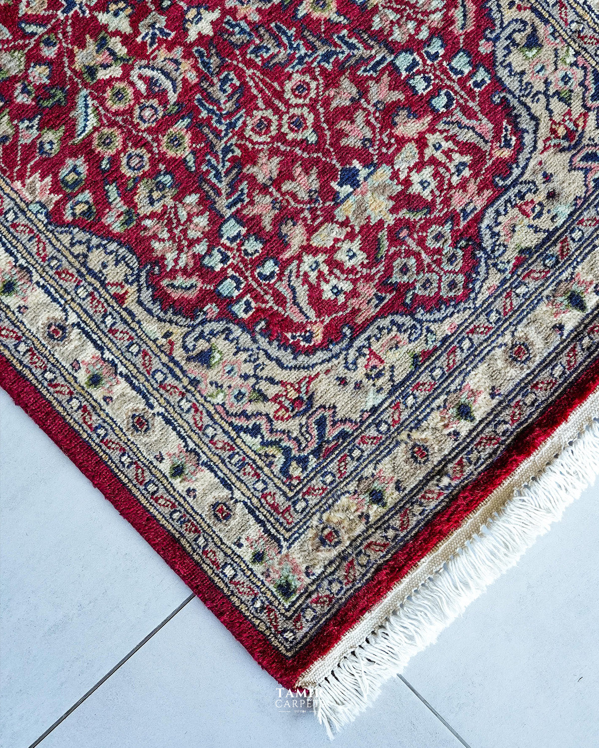 Corner of the red runner showing the ivory border and fringe