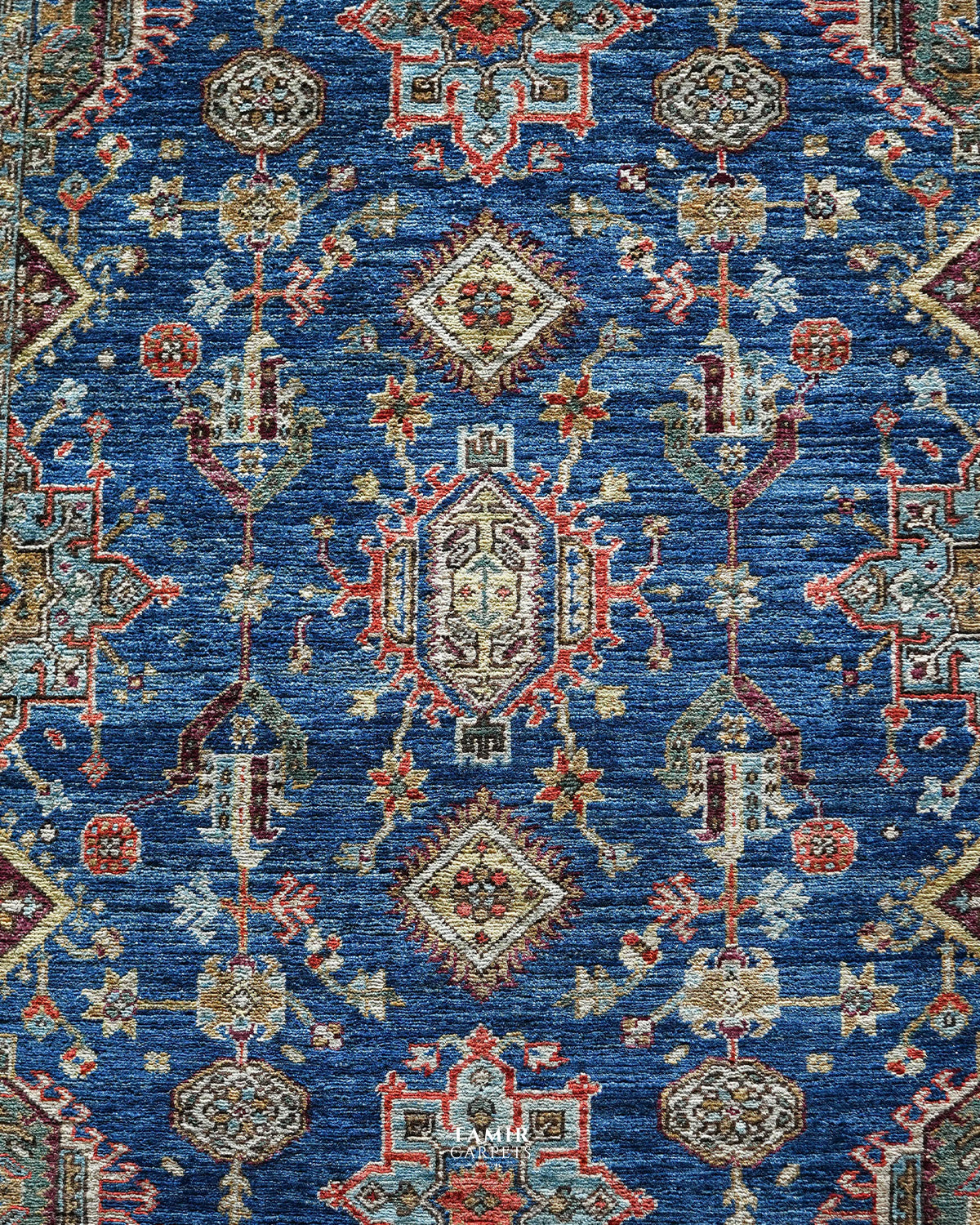 Detail of the red, gold and aqua motifs on the blue Kazaak rug