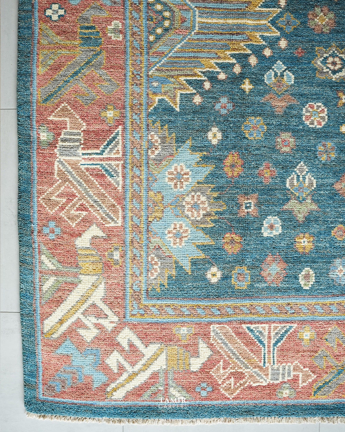 Corner of the blue and pink Oushak rug showing the geometric border