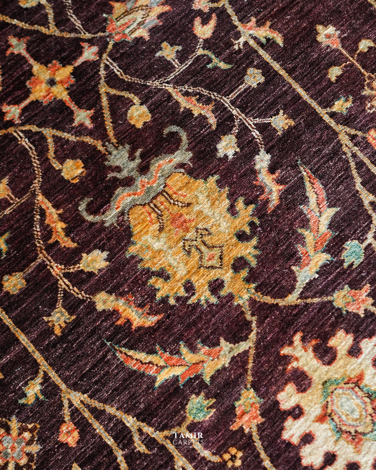 Detail of flowing floral vines across the brown Oushak Afghan rug