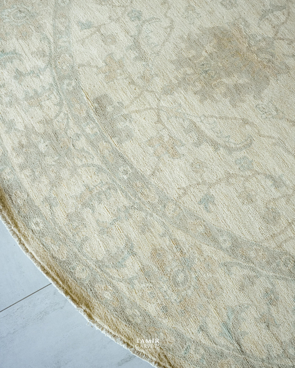Soft sage and sand floral vines along the edge of the round rug