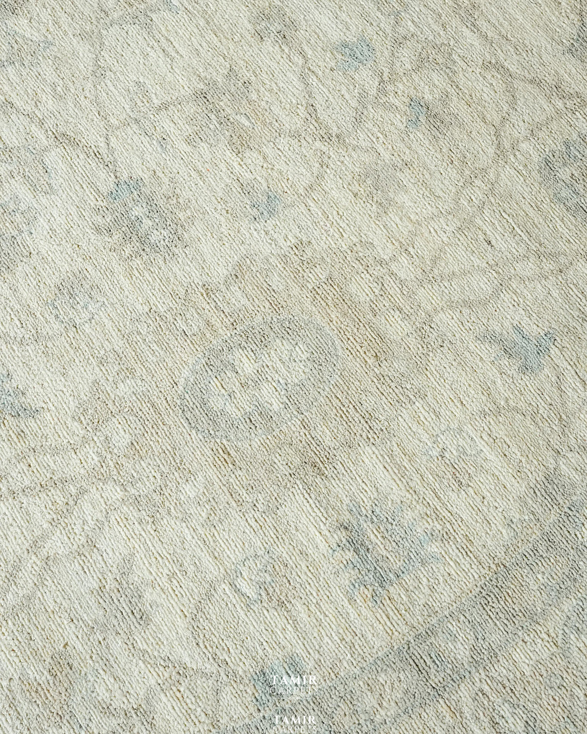 Close-up of pale blue and sand floral motifs in organic handspun wool
