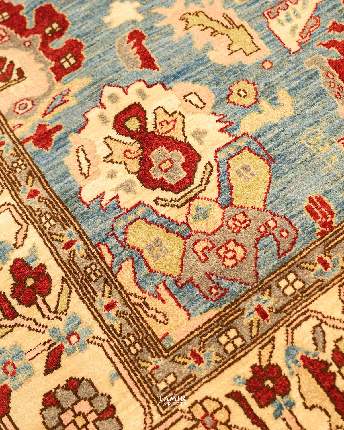 Close-up of red and cream floral motifs on the sky blue Sultanabad field