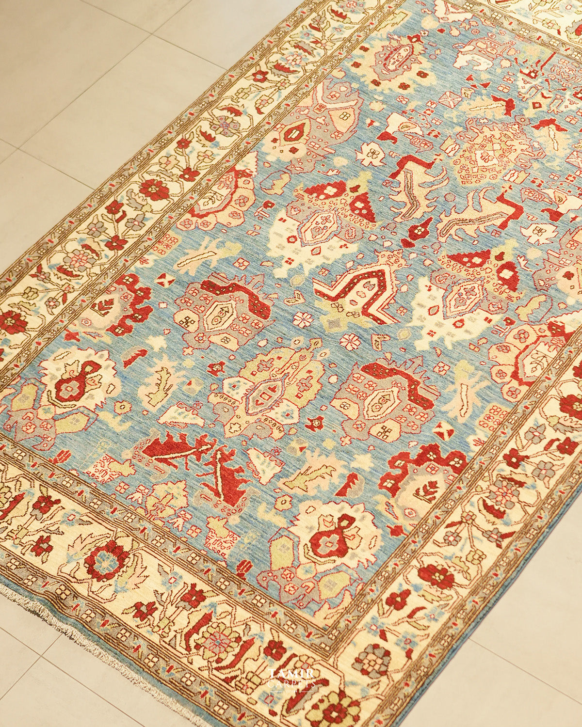 Angled view of the Sultanabad rug's red and cream palmette design