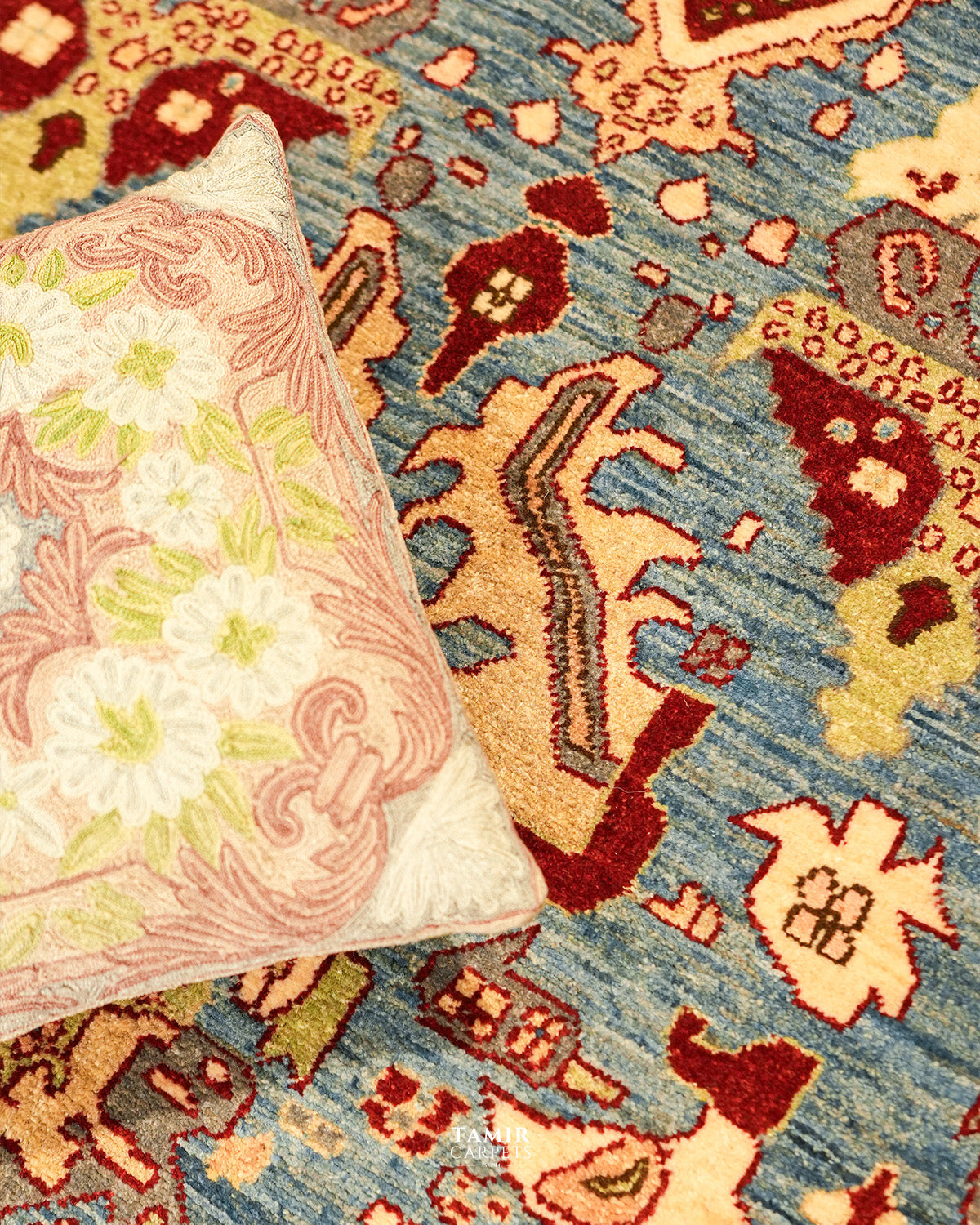 Sultanabad rug styled with a cushion, showing red and blue motifs