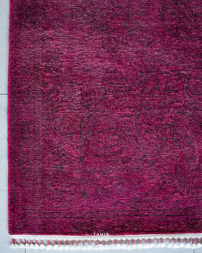 Corner of the magenta overdyed rug with faded vintage pattern and fringe